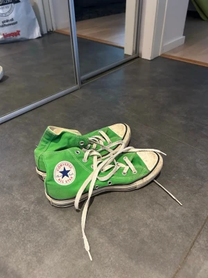Gröna Converse All Star high tops - Snygga gröna Converse All Star high tops med klassisk vit tå och vita snören. Skorna har den ikoniska loggan på sidan och är tillverkade i canvas med gummisula. Perfekta för dig som vill sticka ut med färg på fötterna.