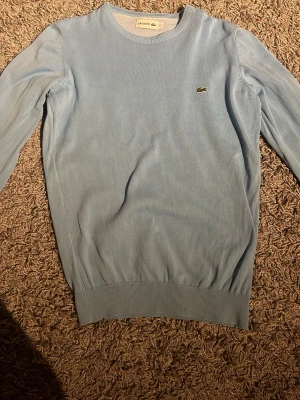 Lacoste tröja - Ljus blå Lacoste tröja i storlek s/xs. Skicket är bra och inga defekter. Väldigt snygg och fräsch, perfekt nu inför sommar kvällarna. Tröjan är även stickad. Hör av er för frågor och sådant. Priset kan diskuteras för snabb affär😁. 