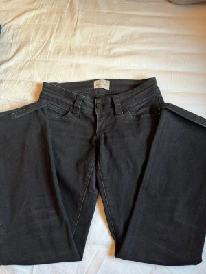 Svarta jeans från Abrand Jeans - Snygga svarta jeans från Abrand Jeans i modellen 00 super low kick lågmidjade jeans med en snygg bootcut . Jeansen är tillverkade i ett mjukt denimtyg som ger en skön passform. Perfekta för en stilren och avslappnad look. Blev tyvärr för små men är otroligt fina!!🌸💞  Storlek: 24 Midjemått: 61 cm Innebens längd: 76 cm