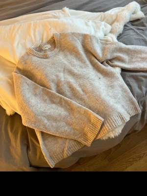 Beige stickad tröja från Gina Tricot - Mysig beige stickad tröja från Gina Tricot i ullblandning. Tröjan har rund halsringning, ribbade muddar och avslappnad passform. Perfekt för lager-på-lager och chill dagar.