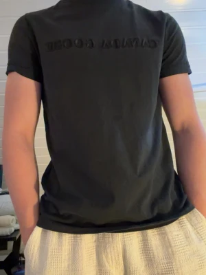 Svart Canada Goose t-shirt - Snygg svart t-shirt från Canada Goose med diskret logga broderad på bröstet. Klassisk rund hals och korta ärmar. Tillverkad i mjuk bomull som känns skön mot huden. Perfekt till jeans eller shorts för en clean och enkel stil.