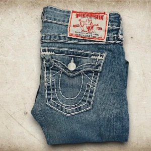 True Religion bootcut jeans blå - Snygga blå bootcut jeans från True Religion med fat stitch. Midjemått: 40 cm (tvärs över), innerbenet: 82 cm, säljer då de kommer inte till någon användning längre :( 