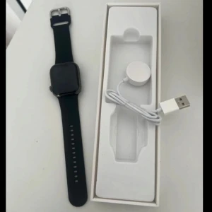 INTE APPLE!! Svart smartklocka med laddare - Säljer en svart smartklocka med fyrkantig skärm och svart armband. Är helt oanvänd. Klockan kommer med en laddare och har så många olika funktioner såsom en apple watch har. Du kan ta bild, ringa, räkna steg, mäta puls osv. Perfekt för den teknikintresserade! Nypris 700kr. Köparen står för frakten 