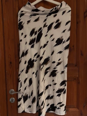 Vit långkjol med svart mönster - Säljer en vit långkjol i satin med svart abstrakt mönster. Kjolen har en rak och flowy passform och är perfekt för dig som gillar en unik och trendig stil. Materialet känns mjukt och följsamt mot kroppen. Använd 1 gång 🌸 (Rekommenderar att ha vita cykelbyxor under då den är lite genomskinlig..)🖤🤍