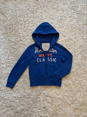 Blå zip hoodie från hollister - Snygg hoodie från hollister. Använd men i mycket bra skick utan defekter. Storlek S!