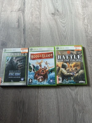 Xbox 360 spelpaket: King Kong, Boog & Elliot, Battle for the Pacific - Tre Xbox 360-spel: Peter Jackson's King Kong (actionäventyr), Boog & Elliot (familjespel) och Battle for the Pacific (krigsspel). Alla i klassiska gröna plastfodral med färgstarka omslag. Perfekt för dig som gillar varierade spelupplevelser.