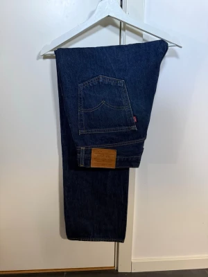 Levi's 555 blå raka jeans - Klassiska blå jeans från Levi's med rak passform och femficksdesign. Jeansen har en tydlig läderpatch bak i midjan och den ikoniska röda Levi's-taggen på bakfickan. Tillverkade i slitstark denim som ger en tidlös look. Storlek 34/30