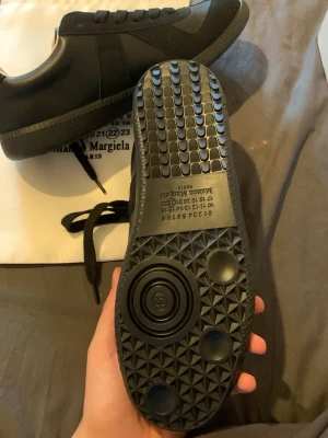 Svarta sneakers Maison Margiela - Snygga svarta sneakers från Maison Margiela med ovandel i mocka och läder. Klassisk låg modell med svarta skosnören och kontrasterande ljus insida. Perfekta för dig som gillar stilrena och exklusiva sneakers. ‼️DM INNAN KÖP‼️