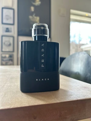 Prada Black parfym 100ml - Helt ny. Snygg parfymflaska från Prada i modellen Black. Flaskan är svart med en stilren, modern design och har en silvrig spraykork. Passar perfekt för dig som gillar exklusiva dofter och vill ha en elegant accessoar på hyllan.