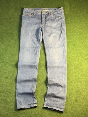 Ljusblå skinny jeans från Kelly - Snygga ljusblå skinny jeans från Kelly med klassisk femficksmodell och guldfärgade detaljer. Jeansen har normal midja och raka ben, sydda i mjukt denimtyg med kontrastsömmar. Perfekta för en avslappnad och trendig look.