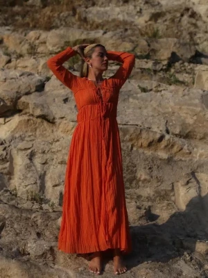 Orange maxiklänning med snörning - Långärmad maxiklänning i stark orange ton med v-ringning och dekorativ snörning framtill. Klänningen har ett lätt, plisserat tyg som ger ett luftigt intryck. Perfekt för sommarens varma dagar. Endast använd vid 2 tillfällen. 