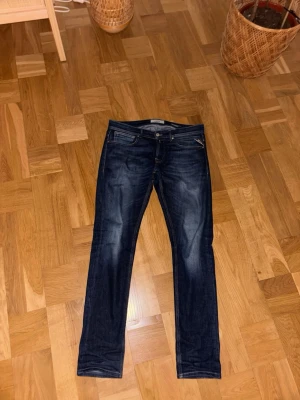 Replay Anbass - Säljer ett par mörkblå slim fit jeans från Replay Jeans med klassisk femficksmodell och snygga slitningar framtill. Jeansen har kontrastsömmar och Replay på bakfickorna. Perfekta för dig som gillar en stilren och modern look. W32 L32
