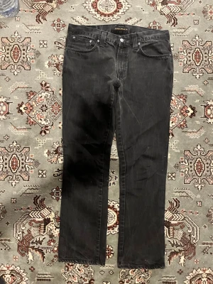 Svarta jeans från Nudie Jeans Dry black denim!!!! Sitter mindre än Weist 36!!!! - Säljer ett par svarta jeans från Nudie Jeans med klassisk femficksmodell och raka ben. Jeansen har en enkel design utan slitningar och är tillverkade i bomull. Perfekta för dig som gillar en clean och stilren look. Fråga gärna om mått