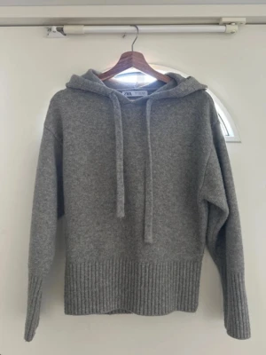 Zara stickad tröja i grått - trendig & mjuk i toppskick - Superfin stickad tröja med luva från Zara i en stilren grå nyans 🤍 Tröjan är i storlek S. Perfekt basplagg som passar till allt - jeans, kjol eller över en tröja på en sen sommarkväll.   ✔️ Väldigt bra skick – knappt använd ✔️ Mjuk och skön kvalitet ✔️ Tidlös design som aldrig går ur stil ✔️ Perfekt för höst, vinter och kyliga sommarkvällar  Den är både bekväm och snygg – ett måste i garderoben! ✨ Säljer eftersom den tyvärr inte används längre.  Skriv vid frågor! Priset kan ändras vid snabb affär.