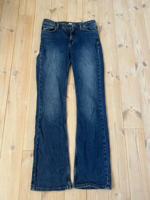 Blå bootcut jeans från Dobber - Snygga blå bootcut jeans från Dobber med klassisk femficksdesign och normal passform. De sitter bootcut och är medel hög i midjan. 