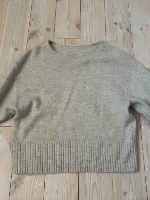 Beige stickad tröja med ribbad kant - Mysig beige stickad tröja med rund hals och bred ribbad kant nedtill. Okänt märke och storlek med runt XS. Vafan är nobbrig se bild 3. 