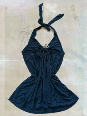 halterneck linnetopp - Säljer en halterneck linnetopp med knyt i nacken och en rund cut-out detalj framtill. Toppen har en ledig passform och är tillverkad i mjukt bomullsmaterial. Perfekt för dig som gillar en unik och trendig look.