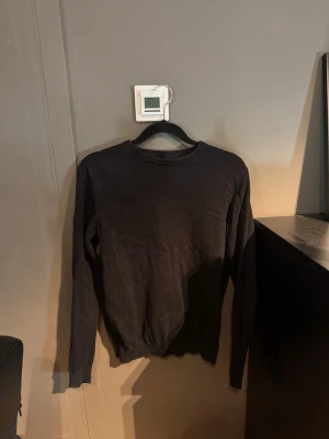 Svart stickad tröja, rund hals - En enkel och stilren svart stickad tröja med rund hals och långa ärmar. Tröjan har ribbade muddar vid ärmslut och nederkant. Perfekt basplagg för lager på lager och funkar till det mesta.