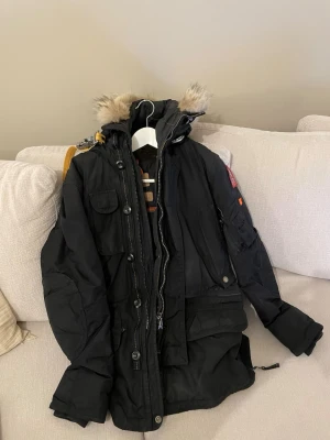 Svart parkas från Parajumpers - Säljer en svart parkas från Parajumpers med avtagbar huva. Storlek S. Legat i garderoben i 2-3 år. Köpt 2019.
