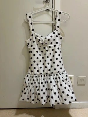  Ny Vit kort prickig klänning från Zara  - Superfin vit kort klänning med svarta prickar och axelband. Klänningen har en söt volang nertill och en lätt figurnära passform. Perfekt för varma dagar och ger en lekfull vibe. Obs det stå L på klänning etiketten men den är lite i storlek upplever som En medium därför säljer jag som en M Stl , egna bilder på annonsen, snabb leverans 