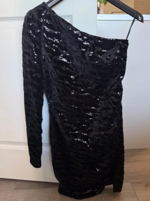 One-shoulder klänning - Svart glittrig oneshoulder klänning med zebramönstrade paljettdetaljer. 