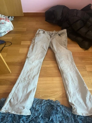 Gråa bootcut jeans - Säljer ett par gråa bootcut jeans med klassisk femficksdesign och normal midja. Jeansen har en avslappnad passform och är perfekta för en trendig vardagslook. Materialet är denim i bomull och färgen är ljusgrå.