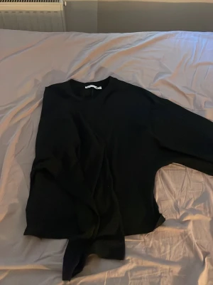 Svart topp  från lager  157 - Säljer en svart topp från lager 157.Toppen har rund halsringning och lång ärm, perfekt för en clean och enkel look. Materialet känns mjukt och lätt, vilket gör den skön att bära till olika outfits.