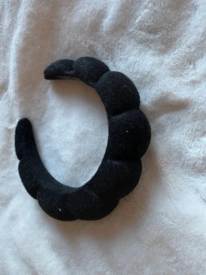 Svart puffigt diadem  - Säljer ett svart diadem med puffig, vadderad design i mjuk sammet. Diademet har en rundad form och ger en trendig look som sticker ut. Perfekt accessoar för att lyfta vilken outfit som helst. 