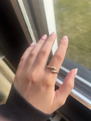 Guldig ring med handmotiv - Unik guldig ring i metall med ett coolt handmotiv som omsluter fingret. Ringen har en öppen design vilket gör att den kan justeras efter storlek. Perfekt för dig som gillar statement-smycken och vill ha något annorlunda.