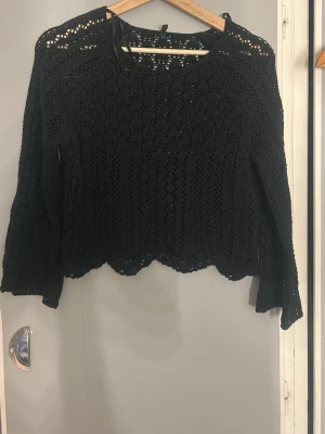 Svart virkad tröja från ONLY - Snygg svart virkad tröja från ONLY i storlek XS. Tröjan har ett genombrutet mönster, långa ärmar och en lätt vågig kant nedtill. Perfekt att styla över ett linne eller topp för en trendig lager-på-lager-look.