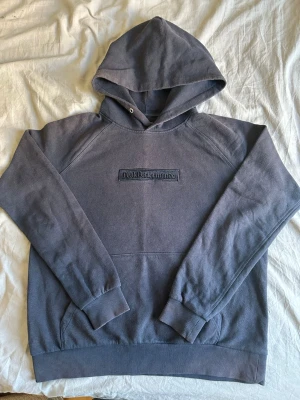 Mörk blåa hoodie från Peak Performance - Svart hoodie från Peak Performance med broderad logga på bröstet. Klassisk modell med huva, dragsko och känguruficka framtill. Tillverkad i mjuk bomullsmix, perfekt för chill eller streetwear.