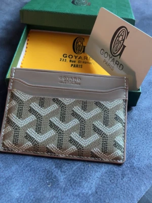 Goy4rd brun korthållare  - Snygg korthållare i brunt och beige med det klassiska mönstret. Tillverkad med läderdetaljer och flera kortfack. Perfekt för dig som vill ha en stilren och exklusiv accessoar från Paris.