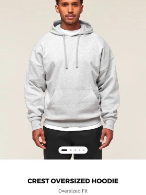 Grå oversized hoodie med huva - Snygg oversized hoodie i ljusgrått från Gymshark. Hoodien har en klassisk huva med dragsko och en stor magficka framtill. Perfekt för en avslappnad och trendig stil. Har endast använt den två gånger så ser nästan ny ut. Ny pris är 549kr