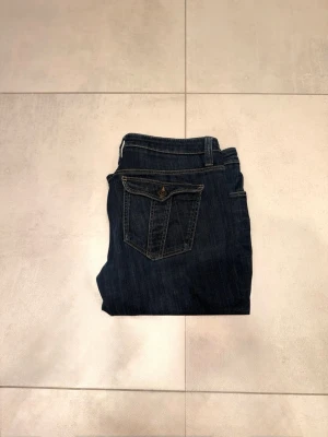 Berberry Jens  - Säljer ett par mörkblå berberry jeans med snygga ficklock och knappdetaljer bak. Lappen där storleken står är bort tvättad men måtten är … (tvärs över midjan = 43cm)  ( längden är 100cm ) OBS: är 100% äkta och ny pris är över 2500kr. Frågor eller funderingar är de bara att ställa !!