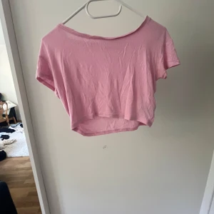 Ljusrosa croppad t-shirt - Säljer en ljusrosa croppad t-shirt med korta ärmar och rund hals. Toppen är enkel och har en loose passform som ger en chill vibe. Perfekt till jeans eller shorts för en avslappnad look. Materialet känns mjukt och lätt mot huden.