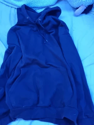 Svart hoodie från Pier One - En klassisk svart hoodie från Pier One med huva och dragsnören. Hoodien har en stor magficka framtill och ribbade muddar vid ärmslut och nederkant. Perfekt för en avslappnad och stilren look.