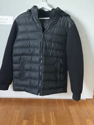 Svart quiltad hoodie-cardigan - Säljer nu min Axel Luxe cardigan då den inte föll mig i smak endast testad en gång mycke gott skick som ny skick, Storlek S. Varm och perfekt till Höst/Vinter. Passar till mycke stilren svart Cardigan