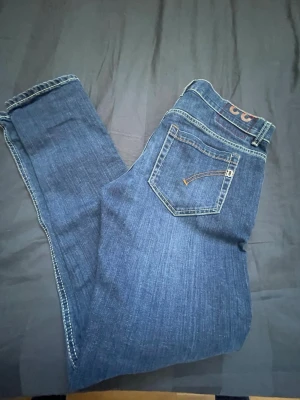 Mörkblå jeans från Dondup - Snygga mörkblå jeans från Dondup med klassisk femficksmodell och kontrastsömmar. Jeansen har knappgylf och en liten logga på bakfickan. Perfekta för dig som gillar stilrena och tidlösa jeans i denim.