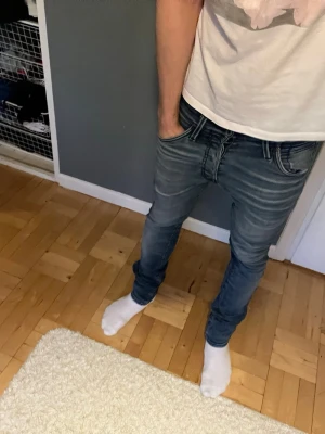 Slim fit blå jeans - Snygga slim fit jeans i mellanblå denim med lätt slitning och klassiska fem fickor. Jeansen har smal passform och normal midja, perfekta för en trendig och avslappnad look. Passar till det mesta och är ett måste i garderoben.