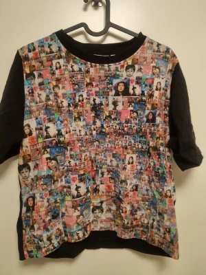 Färgglad t-shirt från Dedicated XS - Unik t-shirt från Dedicated i storlek XS med svart bas och färgglatt collage-mönster framtill. T-shirten har korta ärmar och är gjord i mjuk bomull. Perfekt för dig som vill sticka ut med en kreativ och cool stil. LALEH MERCH från sommaren 25. 