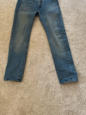 Blå raka jeans från Levi's - Klassiska blå jeans från Levi's med rak passform och fem fickor. Jeansen har en snygg tvättad look och är tillverkade i slitstarkt denim. Perfekta för dig som gillar en tidlös och avslappnad stil. Selvege denim använt fåtal gånger!