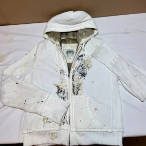 Vintage fur Y2k zip-up - Hoodien har ribbade muddar, två fickor fram och ett unikt svart och gult tryck på framsidan. Perfekt för dig som gillar streetwear och vill ha något extra mysigt.