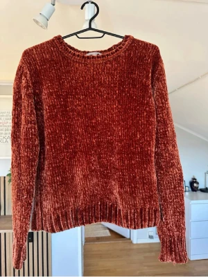 Rostbrun chenilletröja Sincerely Loved - Mysig rostbrun stickad tröja från Sincerely Loved i mjuk chenille. Tröjan har rund halsringning, långa ärmar och ribbstickade muddar vid ärmslut och nederkant. Perfekt för kalla dagar och ger en trendig look.