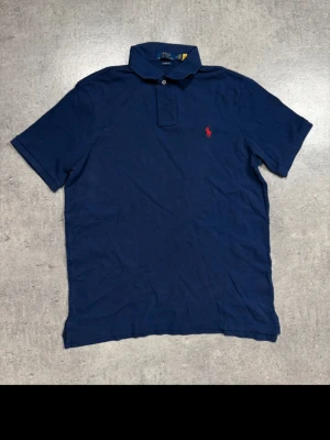 Ralph Lauren piké – marinblå M - Marinblå piké från Ralph Lauren i storlek M.  Klassisk färg som alltid funkar, enkel att matcha till allt.  Mycket bra skick. Säljs pga rensning.  Pris: 400 kr (kan diskuteras vid snabb affär)