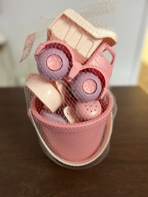 Rosa strandset med lastbil och formar - Ett strandset i rosa och ljuslila plast med en liten lastbil, hink, spade, skopa och djurformar. Perfekt för lek i sandlådan eller på stranden. Setet är lätt att bära och alla delar matchar i färg och stil. 100% giftfritt 