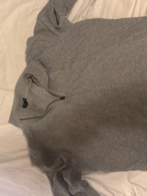 Grå halvzip tröja från Polo Ralph Lauren - Snygg grå långärmad tröja från Polo Ralph Lauren med halv dragkedja och liten broderad logga på bröstet. Perfekt för en avslappnad men stilren look. Mjuk bomullskvalitet och klassisk passform.