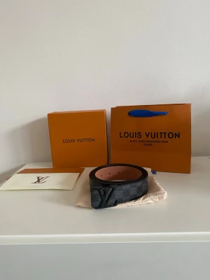 Svart rutigt bälte - Snyggt  bälte  med svart spänne. Bältet är gjort i canvas med läderdetaljer och har den klassiska rutiga designen i svart och grått. Perfekt accessoar för att lyfta din outfit.