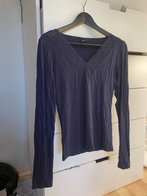Marinblå spets långärmad topp Gina Tricot - Marinblå långärmad topp från Gina Tricot med v-ringning och spetsdetaljer längs halsringningen. Mjukt och tunnare material. Storleken är M men den är lite mindre i storlek och sitter ganska tajt!