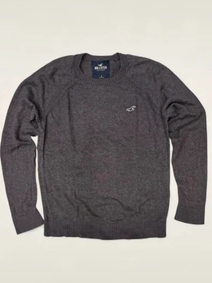 Mörkgrå stickad tröja Hollister - Mörkgrå stickad tröja från Hollister med rund halsringning och diskret logga broderad på bröstet. Tröjan har långa ärmar och ribbade muddar vid ärmslut och nederkant. Perfekt för lager på lager och enkel att matcha. Storlek S men jag skulle säga att den passar som xs. Den är i riktigt fint skick men har ett pyttelitet hål på sidan(se på sista bilden) men hålet syns absolut inte vid användning. Hör av dig vid funderingar!