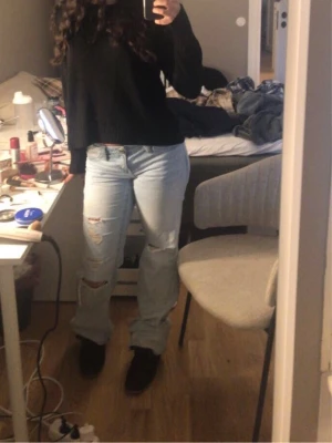 Ljusblå ripped jeans med relaxed fit - Säljer ett par ljusblå jeans med relaxed fit och slitna detaljer på båda benen. Jeansen har klassisk femficksmodell, låg midja och raka ben. Perfekta för en avslappnad och trendig look. Materialet är denim i bomull.